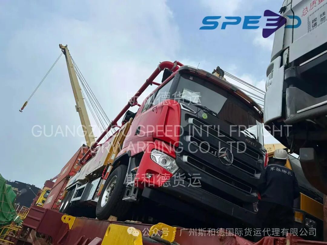Heavy-duty red dump truck being hoisted onto the vessel